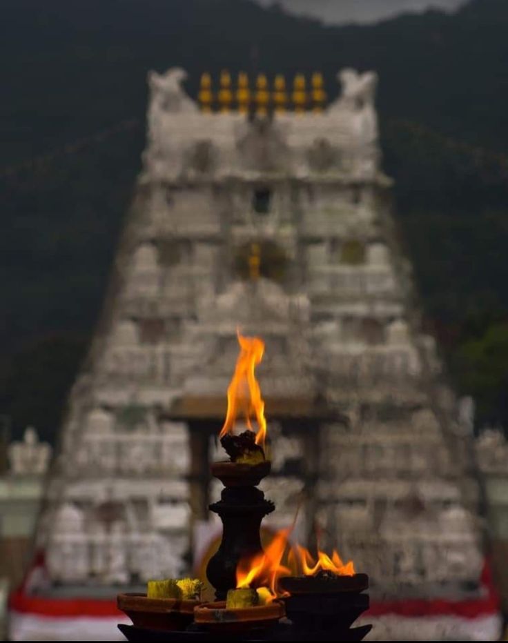 flames are lit in front of a temple