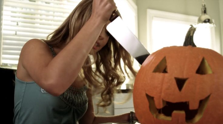 a woman carving a pumpkin with a large knife