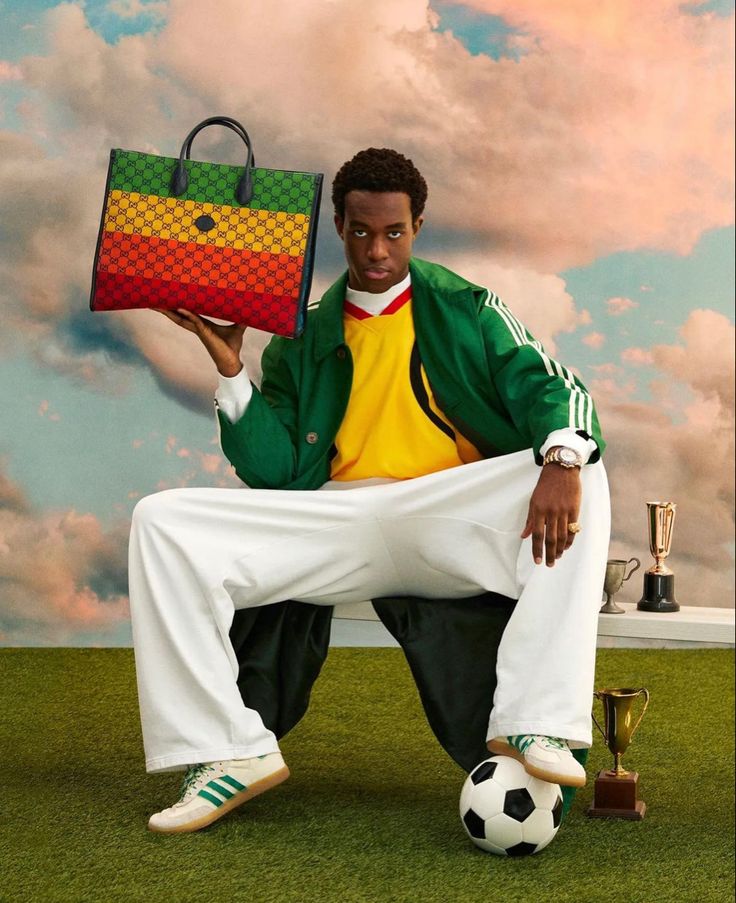 a man sitting on the ground with a bag and soccer ball in front of him