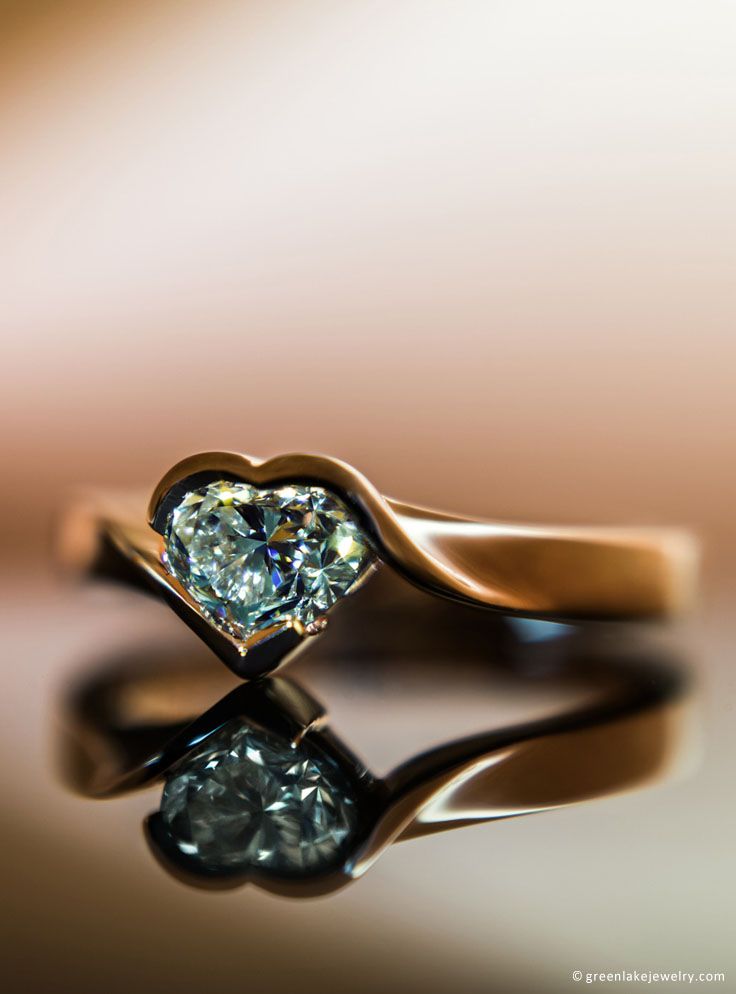 a heart shaped diamond ring sitting on top of a table