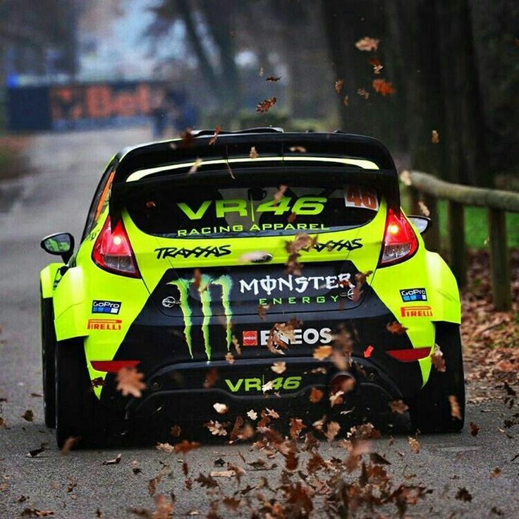 a yellow car driving down a road with leaves on the ground