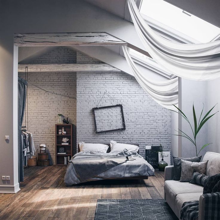 a bedroom with white brick walls and wooden flooring is pictured in this image, there are two couches on either side of the bed