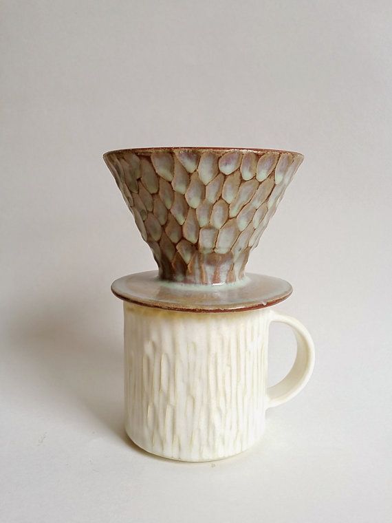 a white cup with a brown pattern on the top and bottom sitting in front of a white background