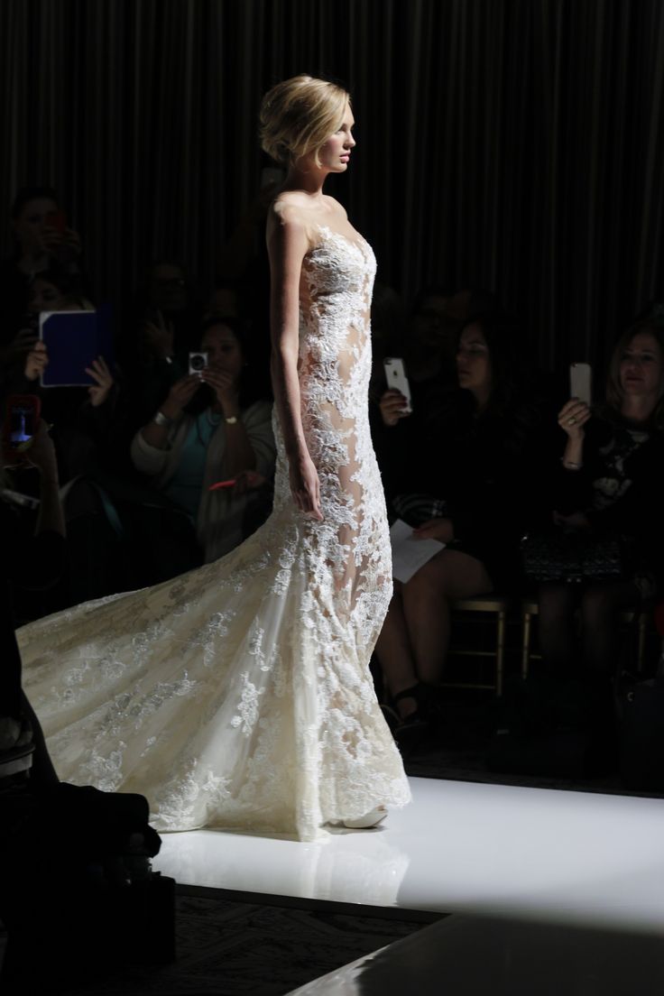 a woman in a wedding dress walking down the runway