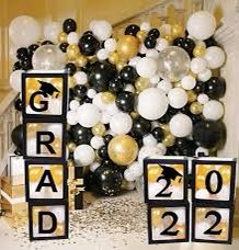 graduation decorations and balloons are displayed in front of a staircase decorated with black, white and gold