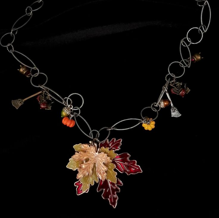 This fairytale witchy necklace is a magical piece intended for those with a heart and soul of fantasy and enchantment. The three-layered maple leaf pendant shimmers in rich fall tones: red, green, and yellow, symbolizing the beauty of autumn. The dangling magical charms include bronze cauldrons, witches with their cauldrons, and brooms - all adding a unique witchy vibe to this extraordinary necklace. Designer attention to detail - take a look into the cauldrons and you'll find a sparkling red cr Magical Charms, Maple Leaf Necklace, Witchy Necklace, Fall Tones, Magic Hands, Witchy Vibes, Brooms, Heart And Soul, Hand Chain