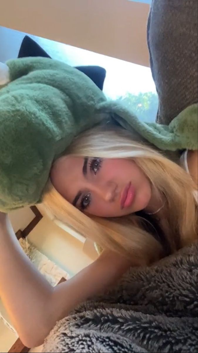 a woman with long blonde hair wearing a green frog hat