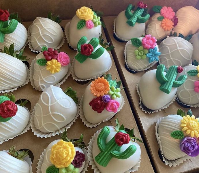 there are many decorated chocolates in the box on this table, including strawberries