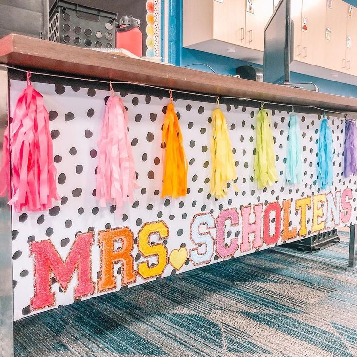 a school desk decorated with colorful tassels and polka dot paper on the wall