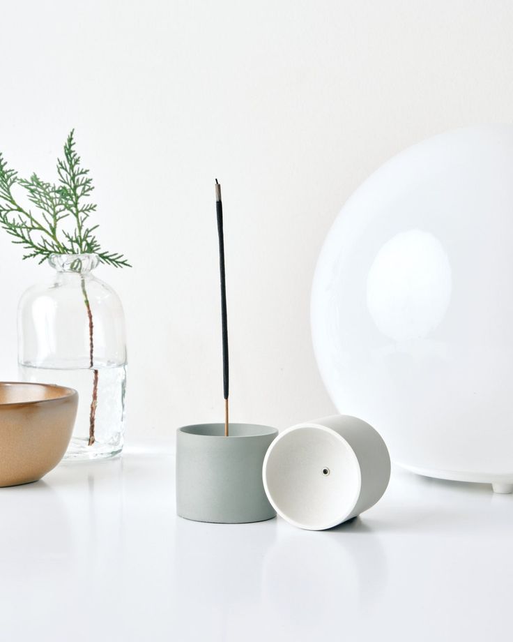 there is a vase, bowl and toothbrush holder next to each other on the table