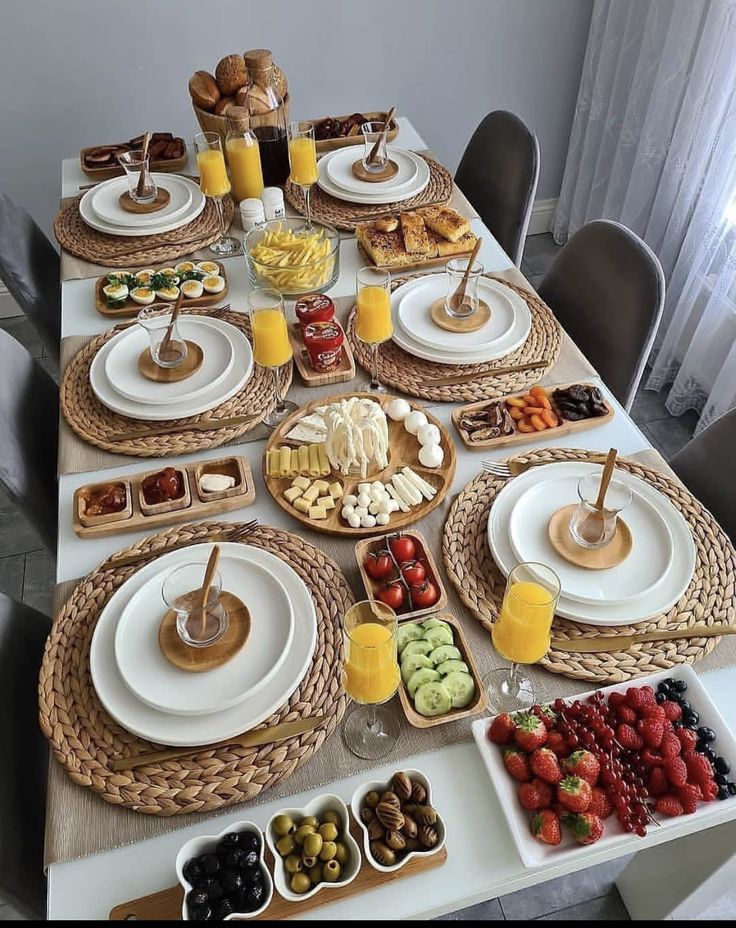 the table is set with plates and bowls of fruit, pastries, and breads