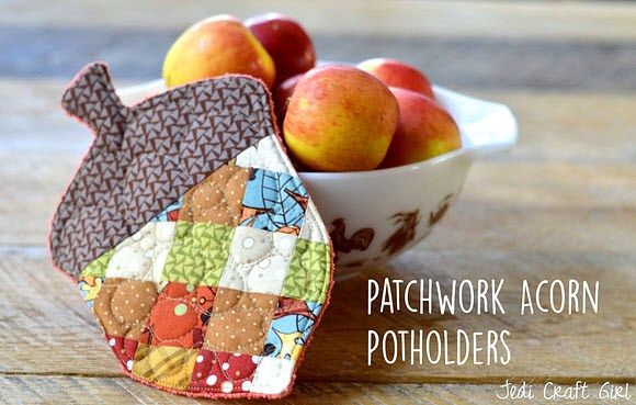 two pieces of fabric are sitting next to a bowl of apples and pears on a wooden table