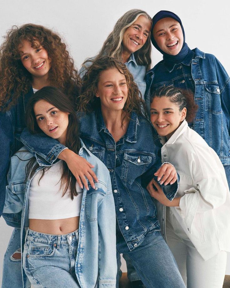 the models are posing together in denim jackets and white tops, with their arms around each other