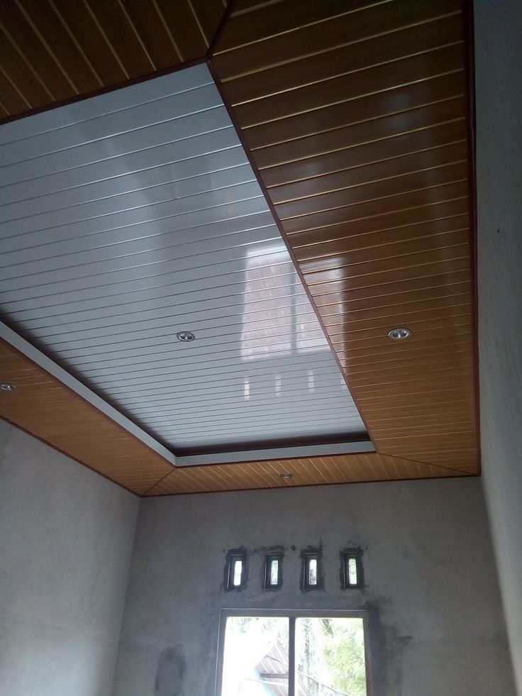 an empty room with a window and wooden ceiling