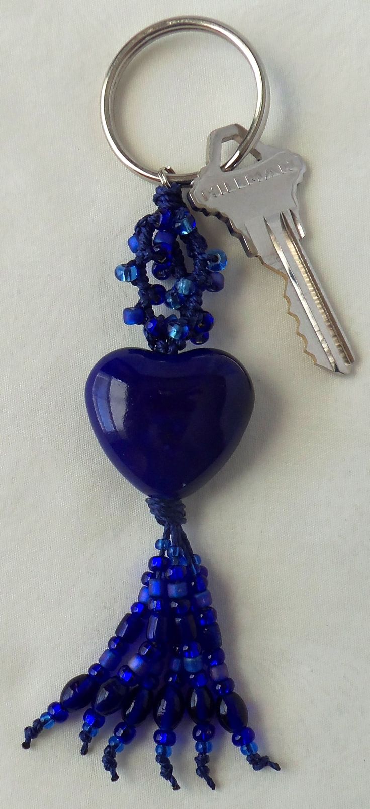 a blue glass beaded keychain hanging from a metal hook