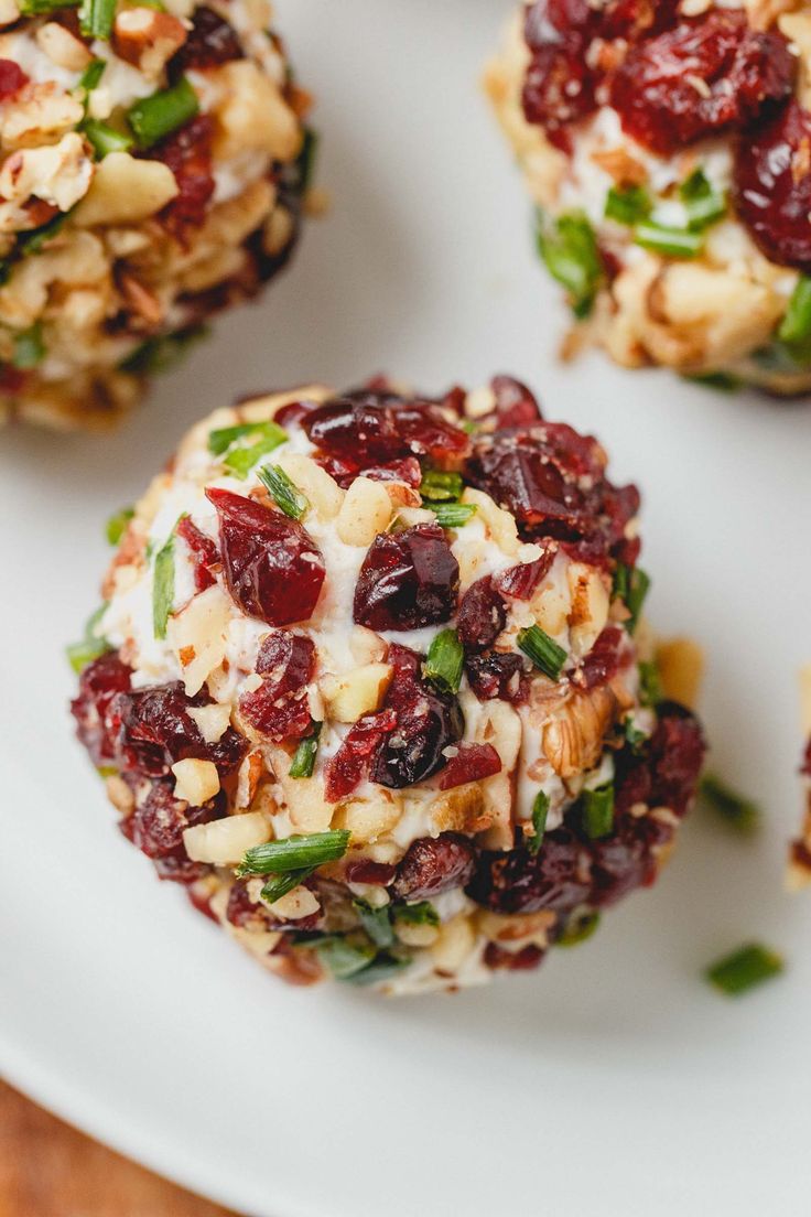 three cookies with cranberry toppings on a white plate next to another cookie