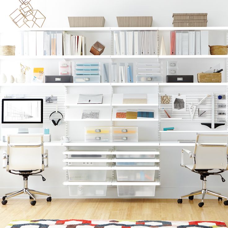 a white desk with two chairs and a computer monitor on it in front of a bookshelf