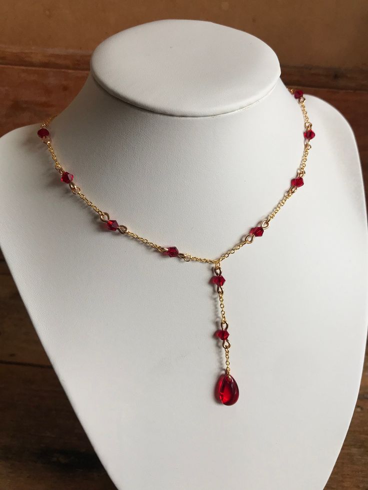 this necklace features a deep, blood-red gemstone, adorned with glass red beads and tarnish resistant chains for those who embrace the darkness with elegance. Red Beaded Ruby Necklace, Red Ruby Beaded Necklaces For Jewelry Making, Gothic Red Jewelry With Chain, Red Beaded Chain Necklace Gift, Gothic Red Necklace With Chain, Red Gothic Jewelry With Chain, Gothic Red Chain Jewelry, Red Beaded Chain Necklace For Gift, Gift Red Beaded Chain Necklace