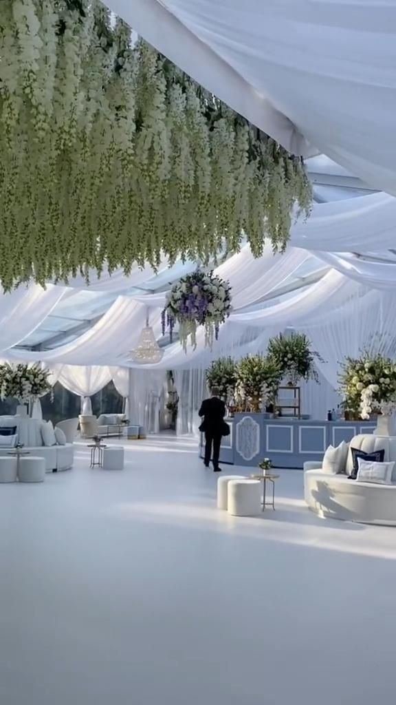 a white tent with couches, tables and flowers hanging from it's ceiling