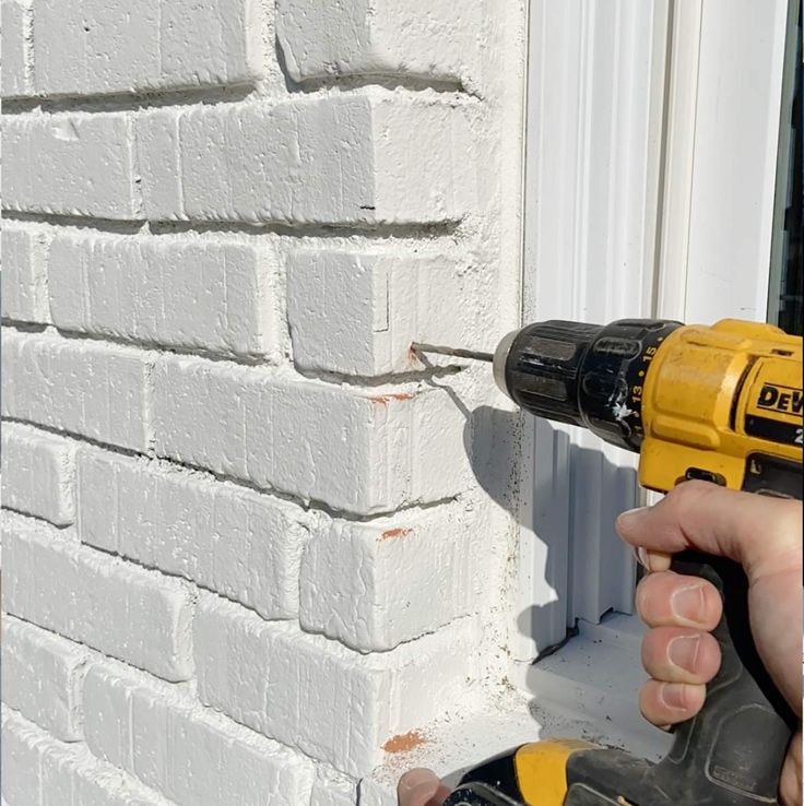 a person using a drill to fix a brick wall with a cordless screwdriver