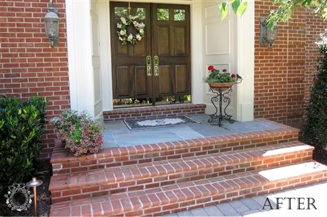 a front door with brick steps and potted plants