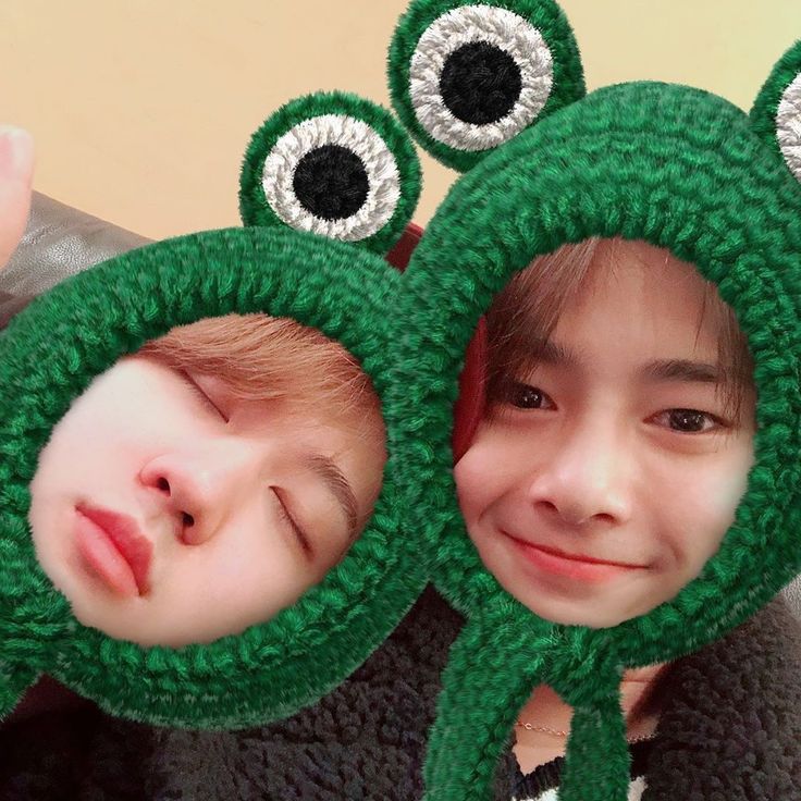 two children wearing green hats with eyes on them