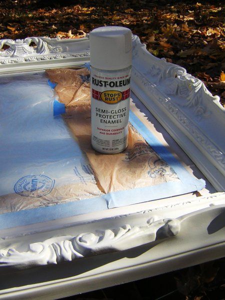 the paint is being applied on an old white frame with leaves around it and in front of it