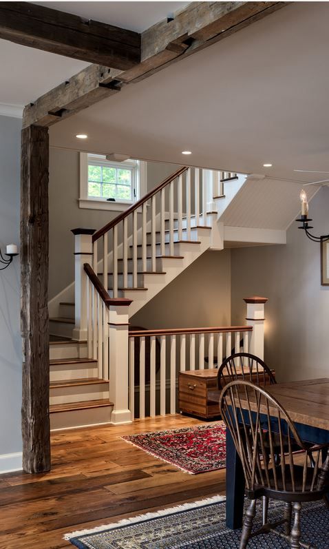 a dining room table and chairs in front of a stair case that leads up to the second floor