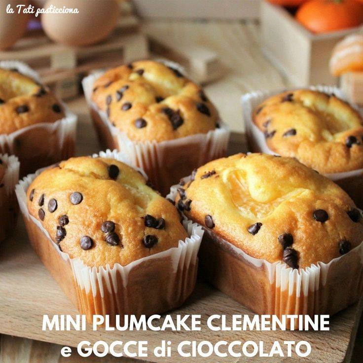 muffins with chocolate chips in them sitting on a cutting board next to oranges