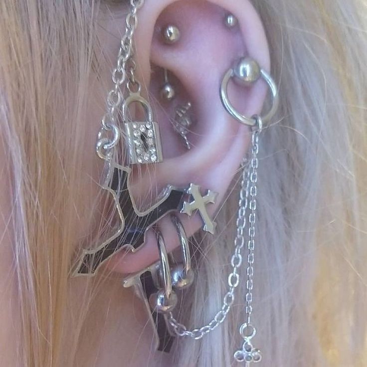 a close up of a person's ear with piercings and chains on it