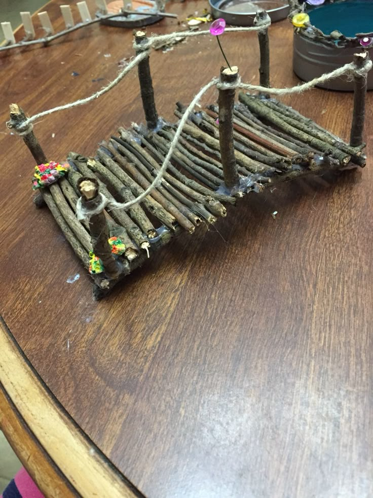 a wooden bridge made out of sticks on top of a table with other items around it