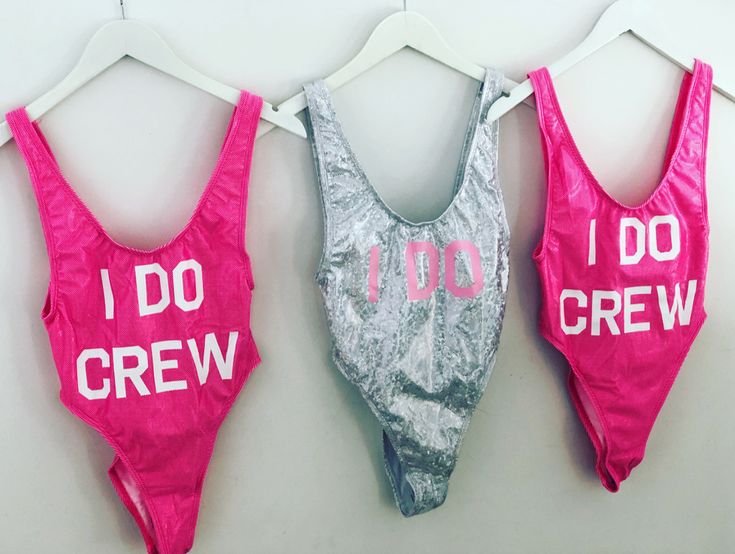 three swimsuits with i do and i do crew printed on them hanging up