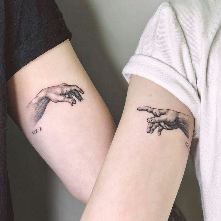 two people with tattoos on their arms holding hands