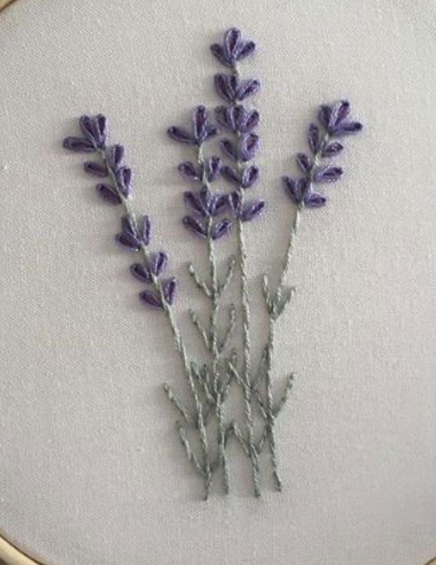 a close up of a embroidery on a white cloth with purple flowers in the middle