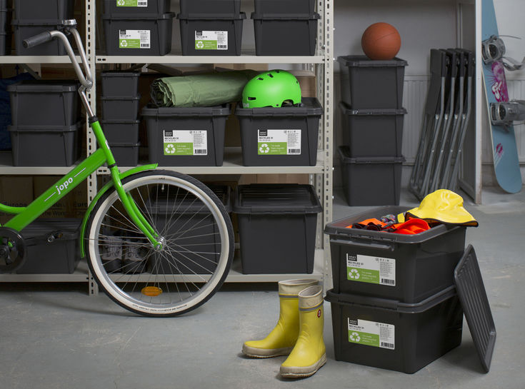 a green bike is parked next to some black boxes and bins with yellow rubber boots