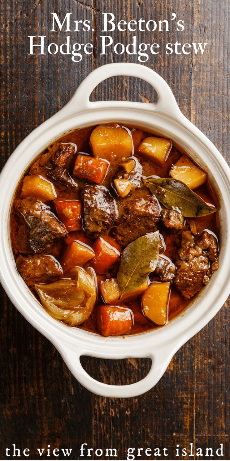 a pot filled with meat and vegetables on top of a wooden table