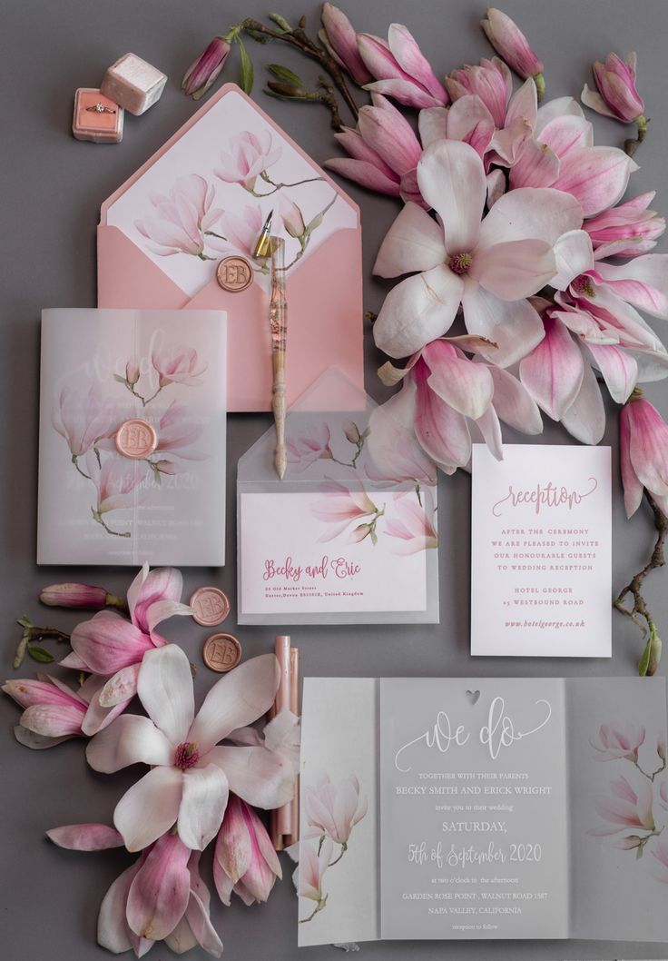 the wedding stationery is surrounded by pink flowers and other things that are on display