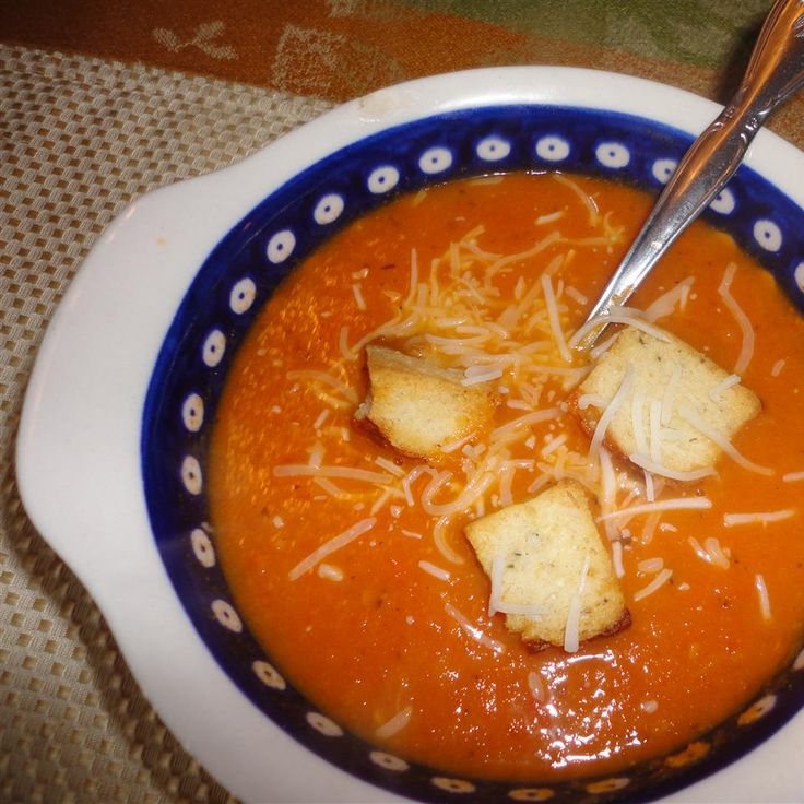 a bowl of tomato soup with croutons and parmesan cheese