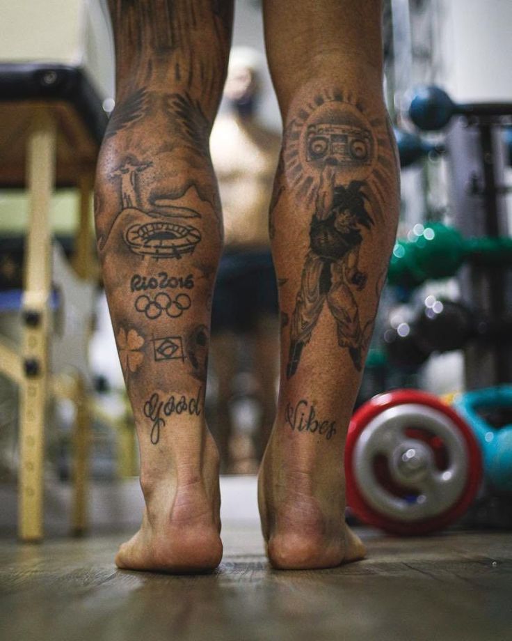 the legs and ankles of a man with tattoos on his body, standing in a gym