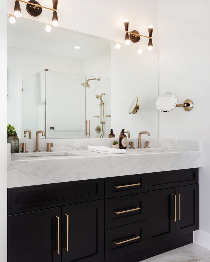 a bathroom with two sinks, mirrors and lights on the wall above them is shown