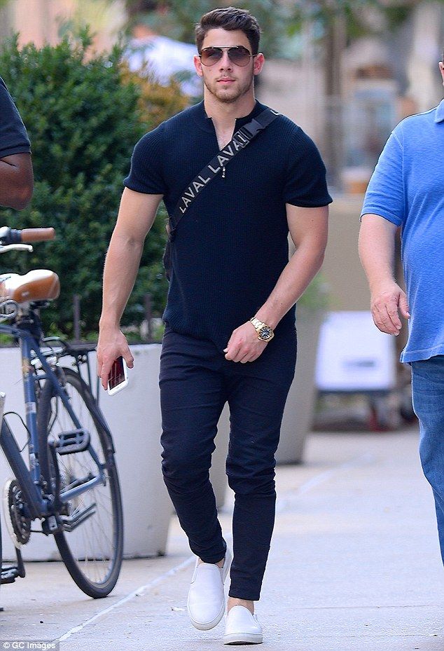 a man walking down the street with his hand in his pocket while wearing sunglasses and a black t - shirt