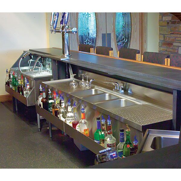 a stainless steel sink with lots of bottles on the bottom and under it, in front of a mirror