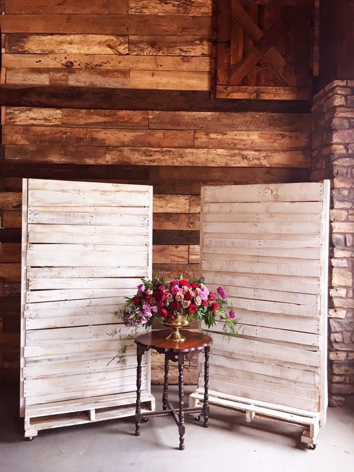 a table with some flowers on it next to two wooden partitions that have been made out of pallets