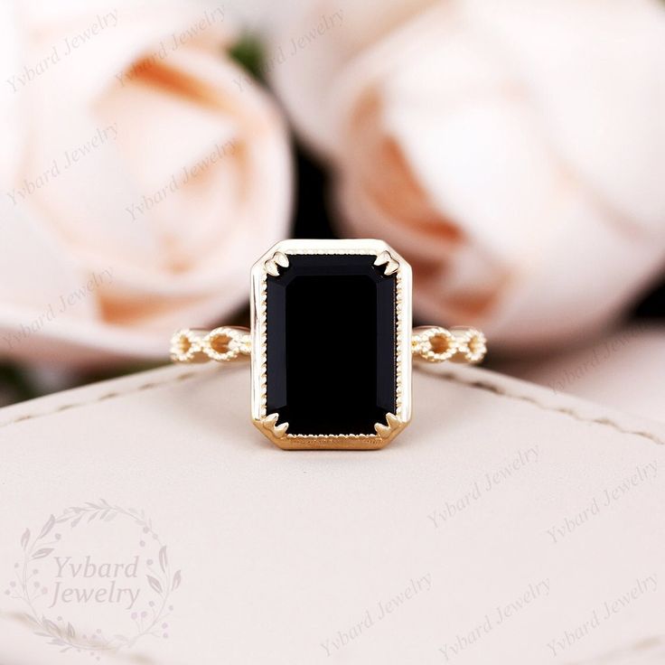 a black stone ring sitting on top of a white box next to flowers and roses