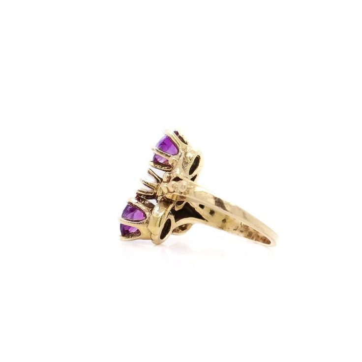 A fine toi et moi gold, amethyst, and pearl cocktail ring.  Size 2.  In 14 karat yellow gold.  The gold setting with a flower to either side of the stones and with decorative rivets/beading.  Set two round cut amethysts with a pearl in the center of the trio of stones. The amethysts have inclusions.  Simply a wonderful ring!  Date: 20th Century  Overall Condition: It is in overall good, as-pictured, used estate condition with some fine & light surface scratches and other signs of expected light wear consistent with age.  Fineness: Marked 14k for gold fineness.   Marks: Marked 14k to the shank.   Ring Size: ca. 2  Gemstone Measurements: 2 Amethyst: ca. 5.5mm diameter x 3.25mm height 1 Pearl: ca. 4mm diameter  Measurements: Height: ca. 17mm Width: ca. 18mm Depth: ca. 21mm  Weight: ca 3.3 g Three Stone Amethyst Ring In Yellow Gold, Yellow Gold Three Stone Amethyst Ring, Marquise Yellow Gold Amethyst Ring Fine Jewelry, Multi-stone Amethyst Ring In Yellow Gold, Fine Jewelry Yellow Gold Marquise Amethyst Ring, Anniversary Yellow Gold Three-stone Amethyst Ring, Heirloom Multi-stone Purple Amethyst Ring, Purple Multi-stone Amethyst Ring Fine Jewelry, Heirloom Multi-stone Amethyst Ring In 14k Gold