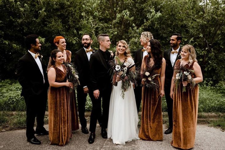 a group of people standing next to each other in front of some trees and bushes