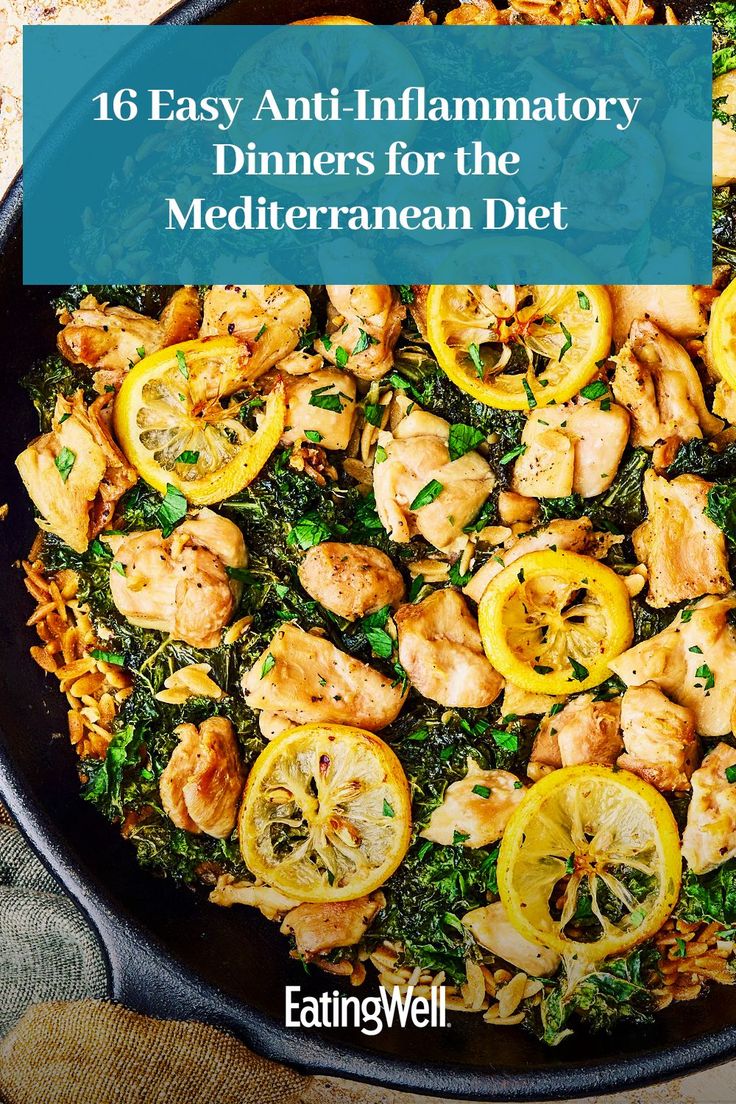 a skillet filled with chicken, lemons and spinach on top of a table