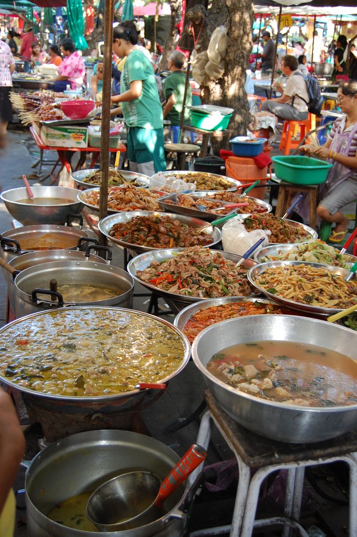 many pans of food are on display at an outdoor market