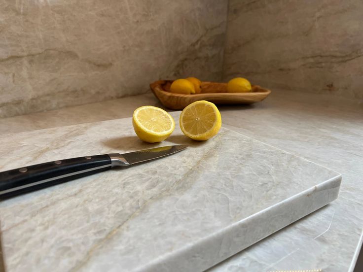 two lemons and a knife on a marble counter top