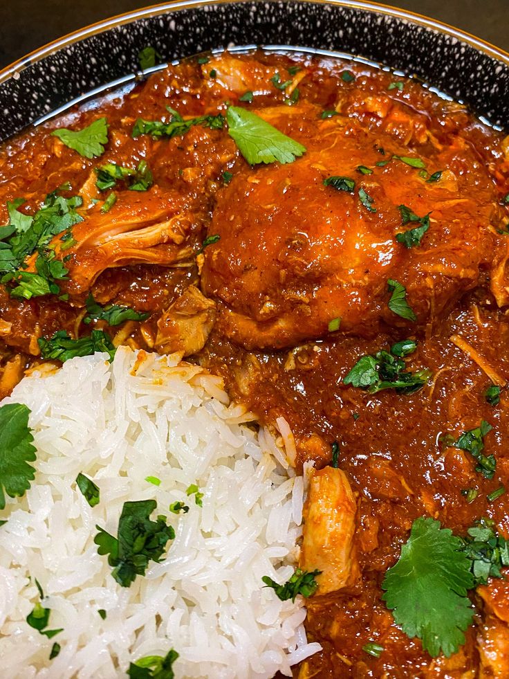 a plate filled with rice and meat covered in gravy, garnished with cilantro